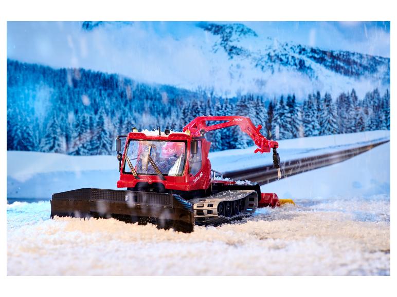 Červený sněžný skútr PistenBully 600 se sněžným pluhem v zimní krajině.