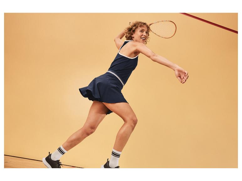 Žena hrající squash v šatech a sukni.