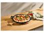 Zeleninová pizza v černé litinové pánvi na dřevěném stole s lněnou utěrkou.