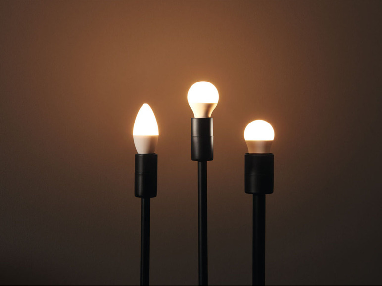 Tři žárovky v různých tvarech v černých lampách.