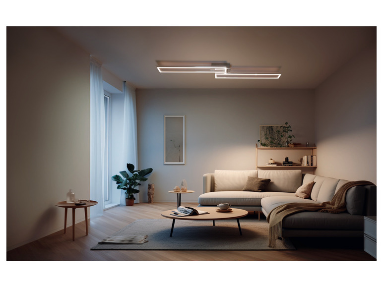 Moderní obývací pokoj s bílým rohovým gaučem a moderním LED stropním svítidlem.