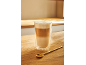 Latte macchiato ve sklenici a zlatá lžička na dřevěném stole.
