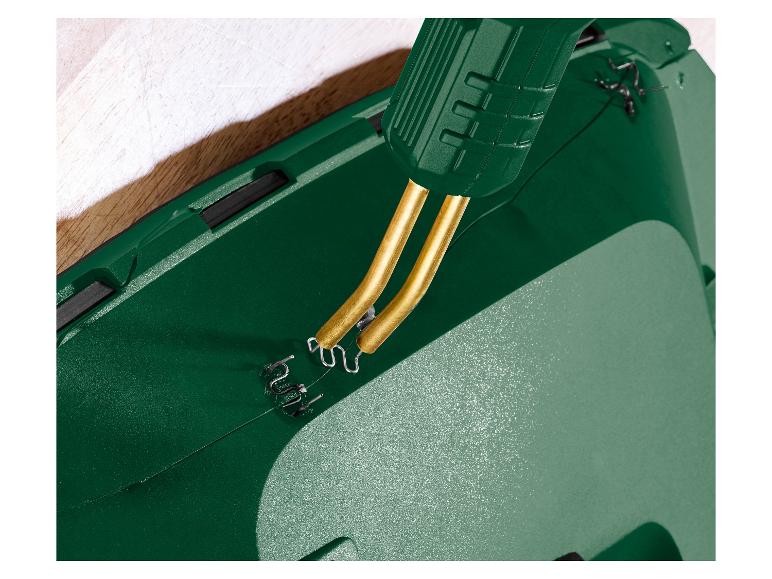 Detail zelené svářečky plastů s kovovými sponkami opravujícími prasklinu.