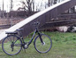 Černý elektrický bicykl značky Colorado Arrow zaparkovaný v trávě.