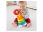 Dítě si hraje s barevnou věží kroužků Fisher-Price na bílém koberci.