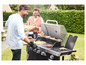 Pár griluje hamburgery, klobásy a kukuřici na černém plynovém grilu.