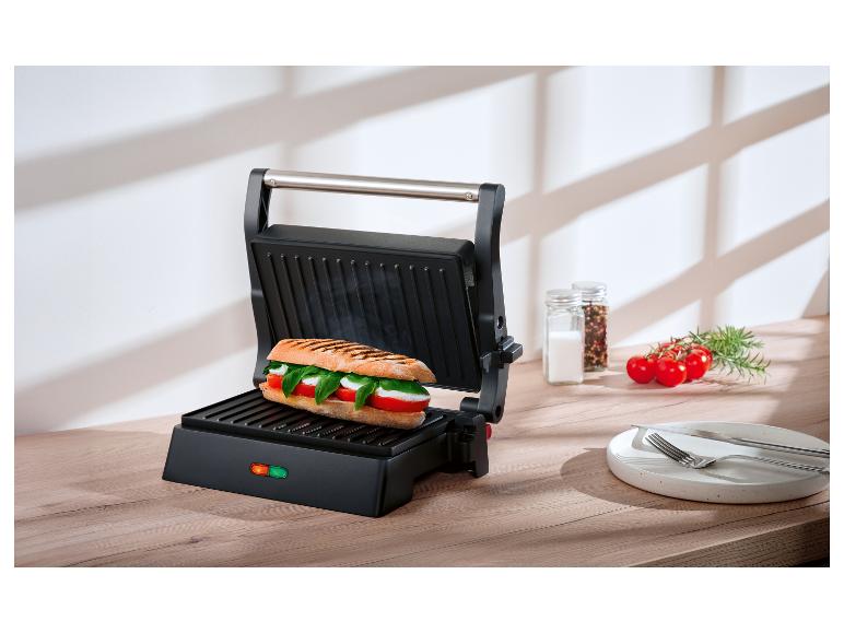Otevřený panini gril s Caprese sendvičem na dřevěné desce.