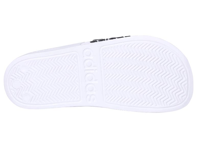 Podešev bílých Adidas pantoflí.