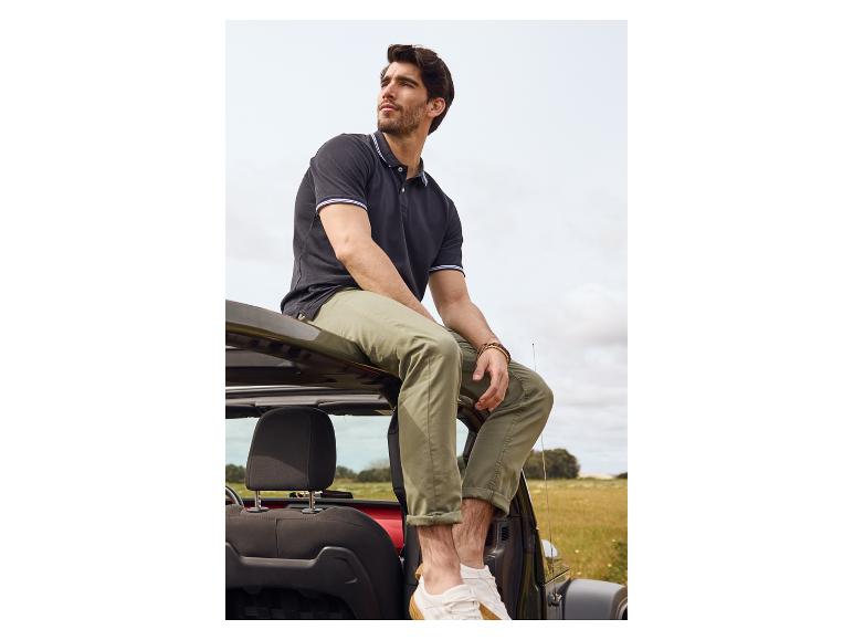 Černé polo, khaki kalhoty a bílé tenisky: uvolněný muž na Jeepu.