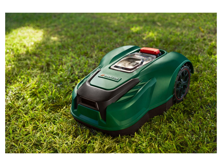 Zelená robotická sekačka Parkside na trávě.