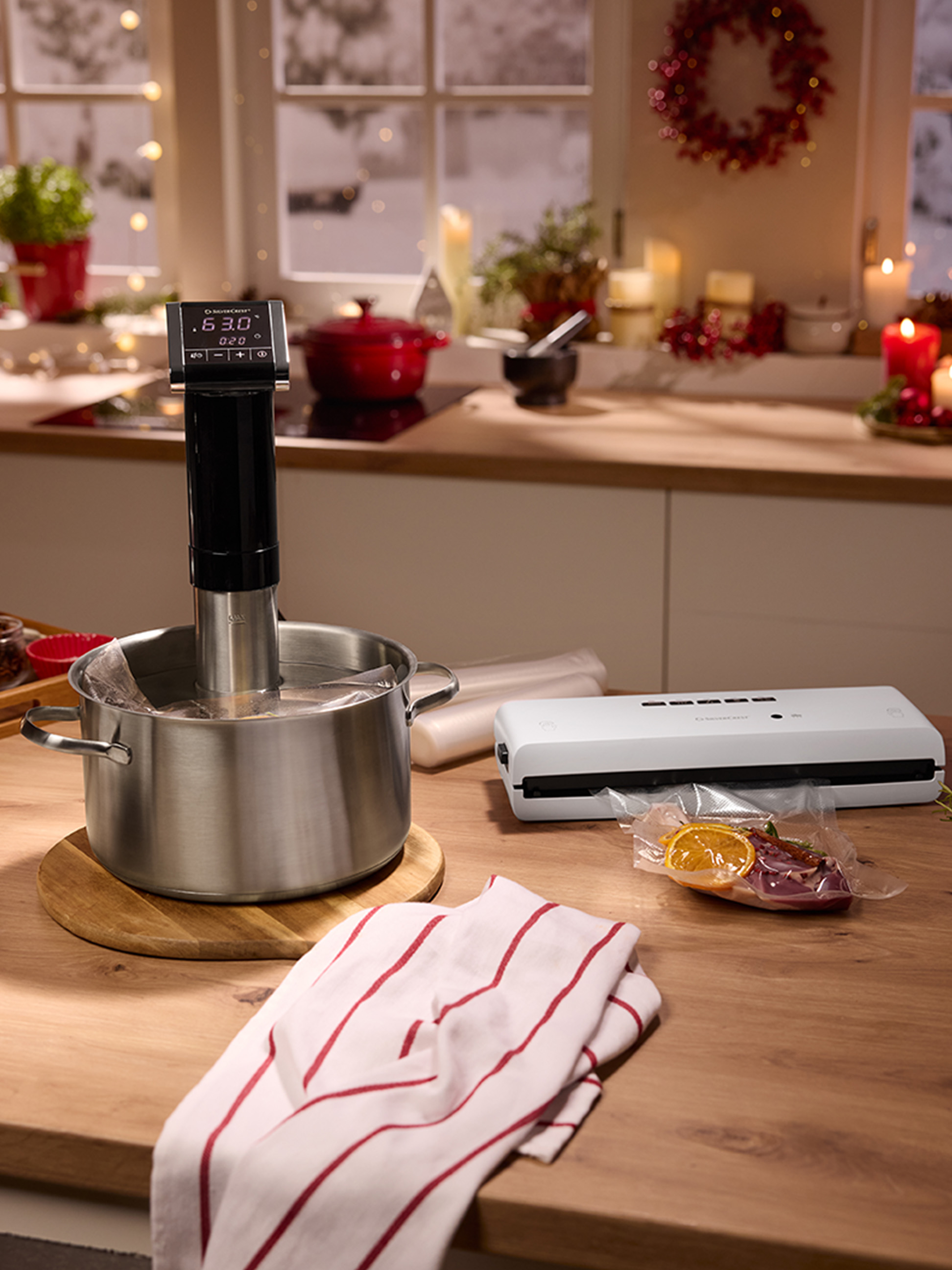 Sous vide vařič a vakuovačka na kuchyňské lince s vánočními dekoracemi.