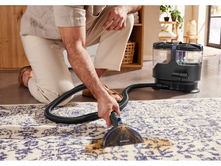Muž čistí koberec tepovačem SilverCrest.