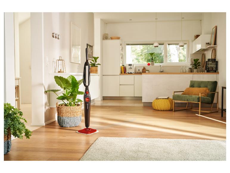 Parní čistič stojí na dřevěné podlaze v moderní kuchyni a obývacím prostoru.