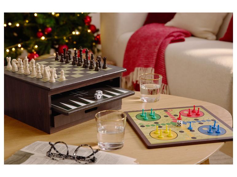 Deskové hry, včetně šachů, backgammonu a Ludo, na konferenčním stolku vedle vánočního stromku.