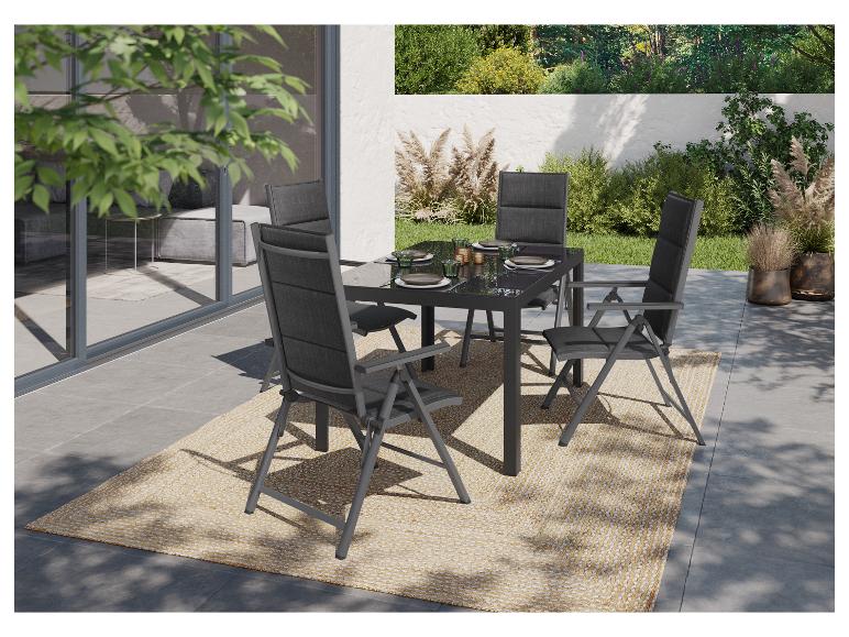 Šedá skládací zahradní sada se stolem a židlemi na jutovém koberci.