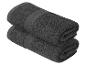Dva tmavě šedé ručníky, srolované a naskládané na sobě.