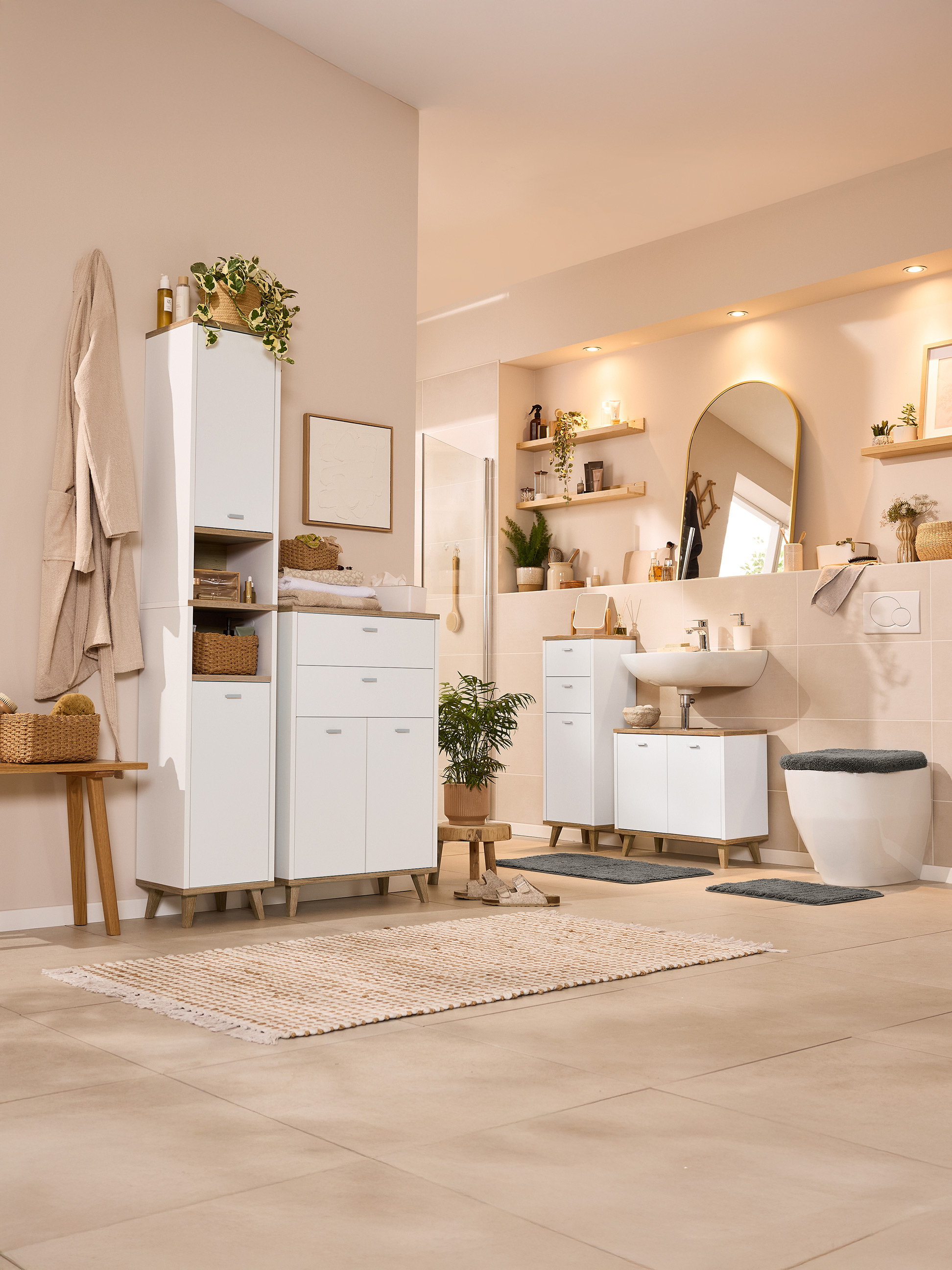 Světlá koupelna s bílým nábytkem, dřevěnými akcenty a rostlinami.