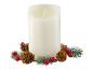 Bílá svíčka s efektem plamene, obklopená větvičkami jehličnanu, šiškami a červenými bobulemi.