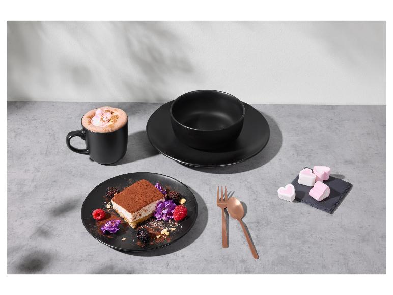 Černé nádobí s dezertem, horkým kakaem a marshmallows na šedém stole.
