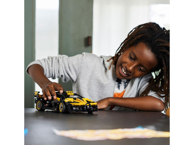 Dítě si hraje se žlutým modelem LEGO Technic McLaren Senna.