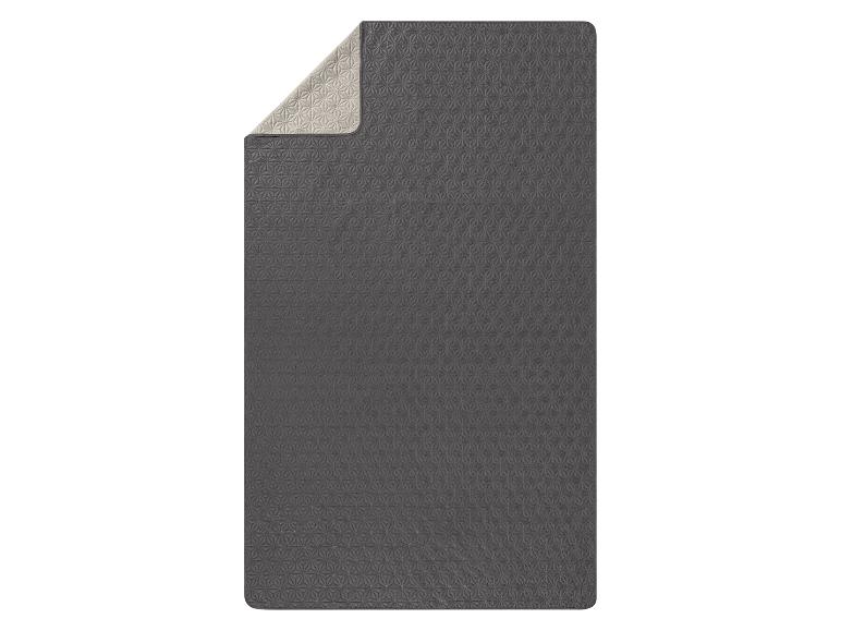 Šedá prošívaná přikrývka s geometrickým vzorem.