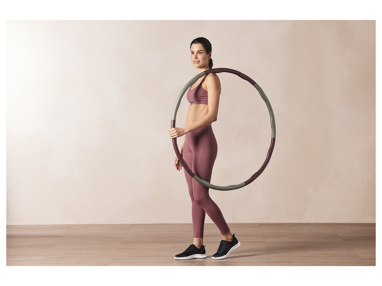 Žena v sportovním oblečení drží fitness kruh.