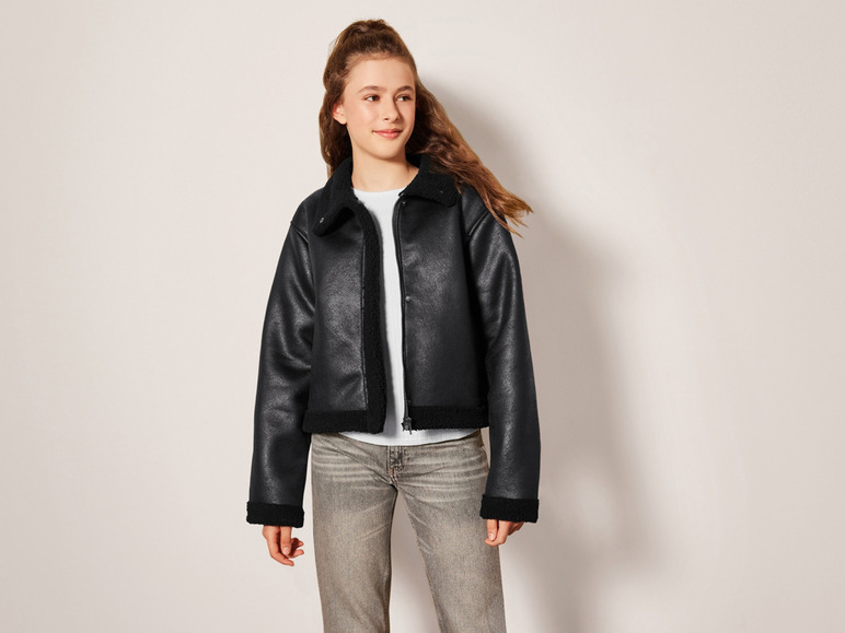 Žena v černé kožené bundě a džínech.