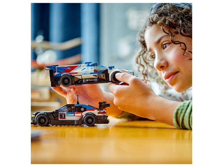 Dítě si hraje s dvěma LEGO závodními auty, včetně BMW M Motorsport.