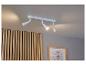 Bílá stropní lampa se třemi reflektory směřujícími na dřevěnou zeď.