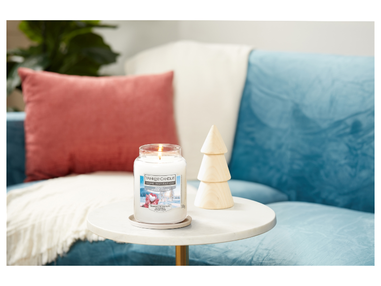 Svíčka Yankee Candle Snow Day na příručním stolku.