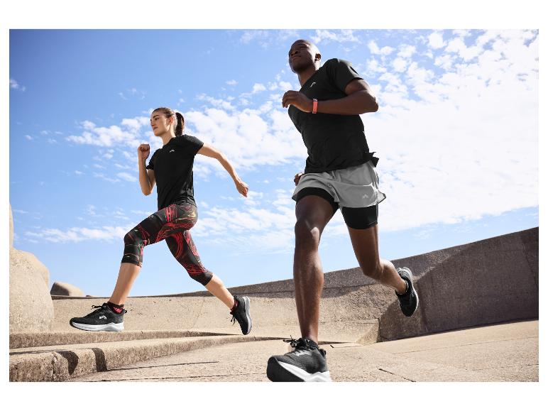 Dva lidé běží venku v černém a šedém sportovním oblečení, s fitness náramky.