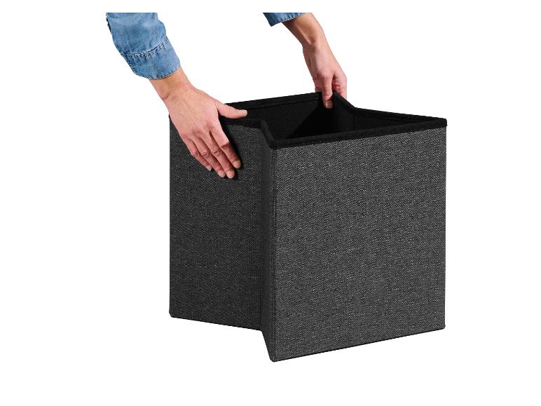 Ruce drží tmavě šedý skládací úložný box, připravený k použití.