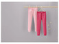 Dvě růžové teplákové kalhoty zavěšené na dřevěném ramínku.