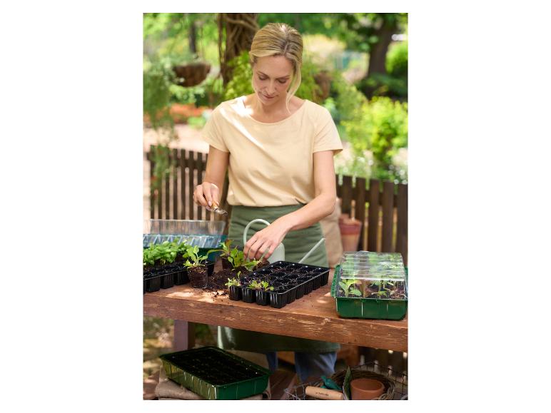 Žena sází semena do sadbovačů a mini skleníků PARKISDE na zahradě.