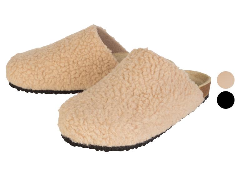 Dva páry měkkých, béžových pantoflí s černou podrážkou.