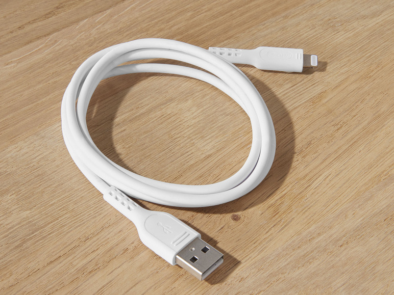 Bílý USB kabel s konektorem Lightning na dřevěném povrchu.