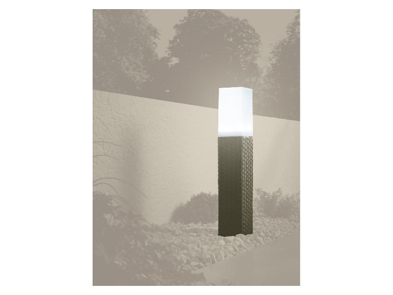 Zahradní lampa s pleteným podstavcem a bílým stínítkem, obklopená oblázky.