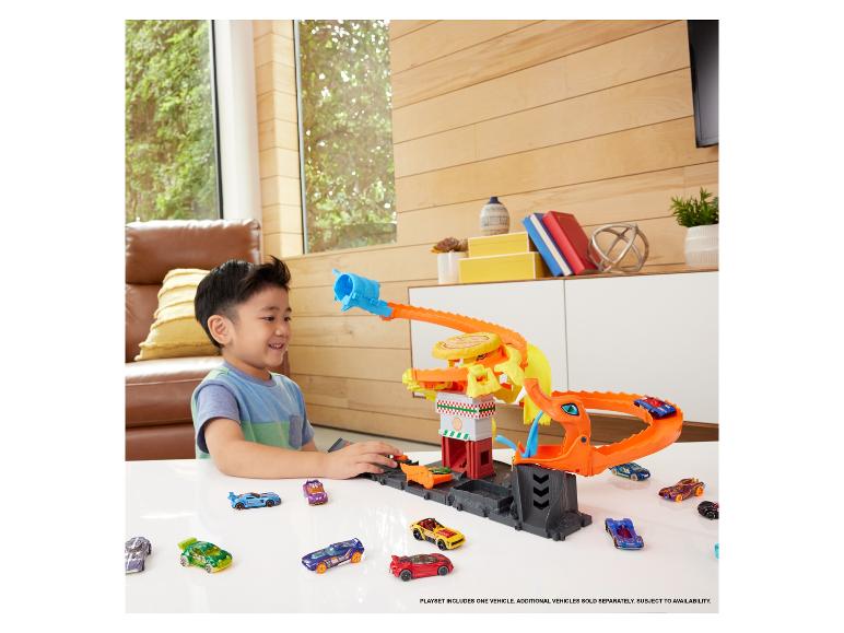 Chlapec si hraje se sadou Hot Wheels s drakem a mnoha autíčky.