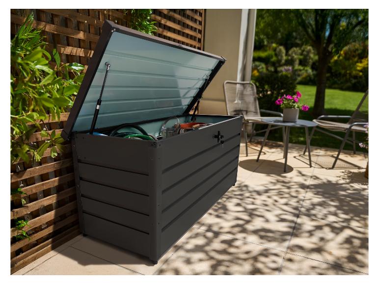 Tmavě šedý venkovní úložný box s otevřeným víkem, plný zahradního nářadí, na terase.