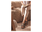 Žena čte knihu sedící na měkké pohovce a nosí sandály typu Birkenstock.