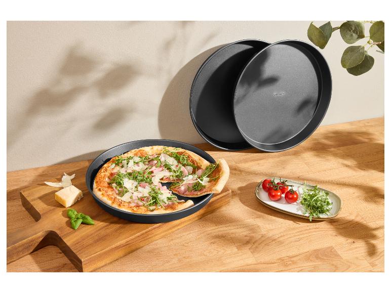 Čerstvě připravená pizza v kulatém pekáči, s rajčaty a rukolou.