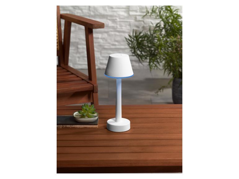 Bílá lampa s tienidlem ve tvaru lampy na dřevěném stole.