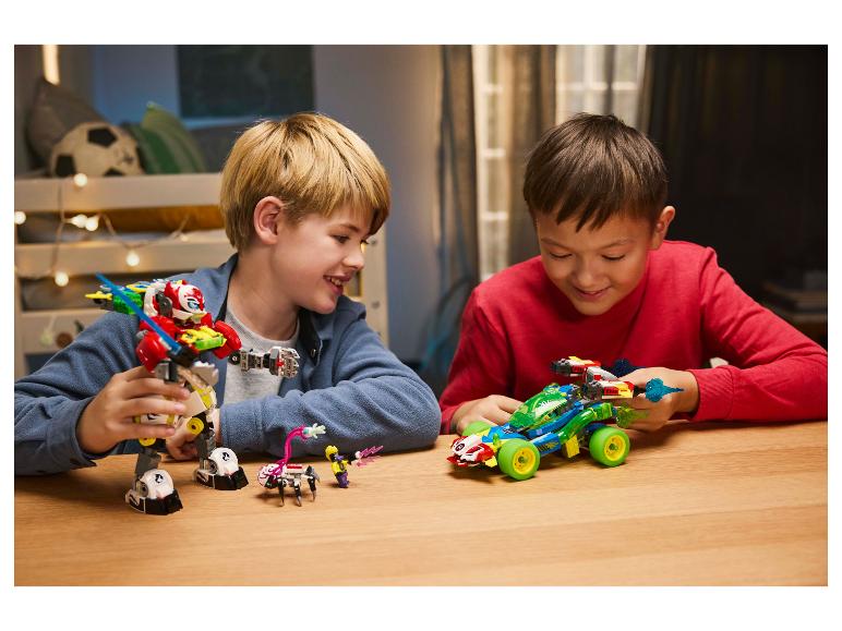 Dva chlapci si hrají s LEGO stavebnicemi, robotem a závodním autem, u dřevěného stolu.