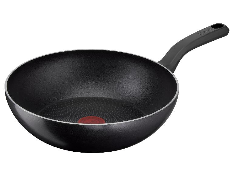 Černá wok pánev s rukojetí a červeným indikátorem teploty na dně.