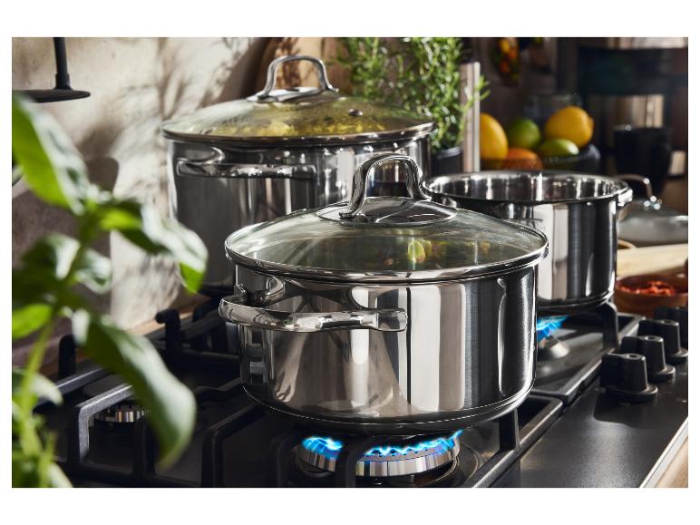 Nerezové hrnce na plynovém sporáku s modrými plameny.