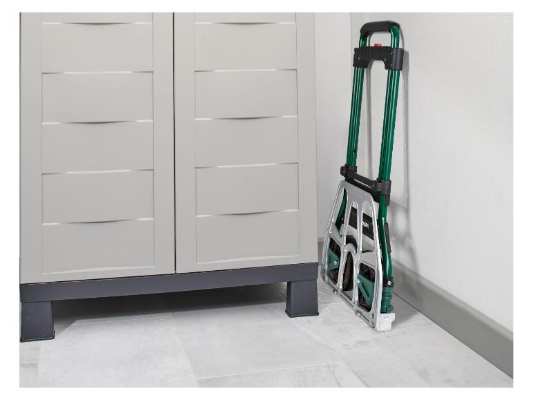 Složený zelený a stříbrný rudl opřený o bílou zeď vedle světle šedé úložné skříně.