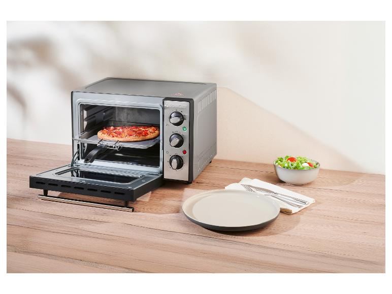Mini trouba SilverCrest s pizzou uvnitř, vedle talíře a misky na salát.