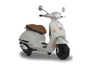 Bílý skútr Vespa s hnědým koženým sedadlem.