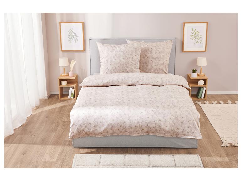 Béžová ložní souprava s květinovým vzorem na šedé posteli.