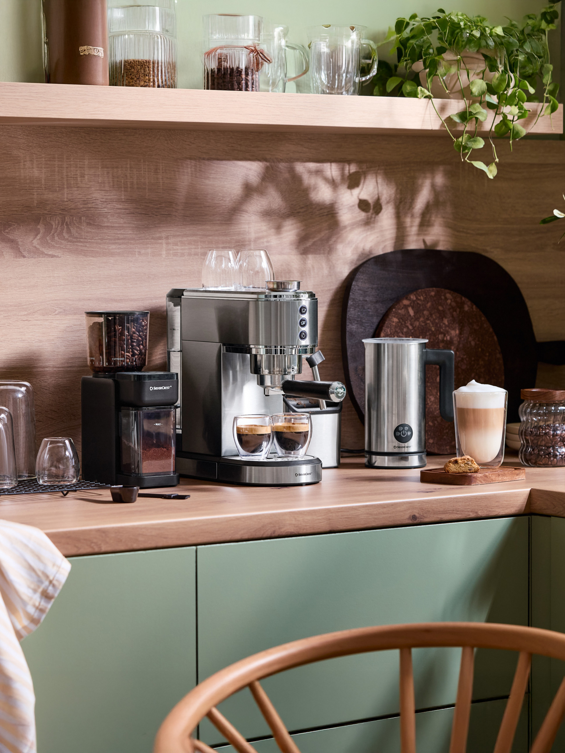 Kávovar SilverCrest a mlýnek na kávu na dřevěné kuchyňské lince se zelenými skříňkami.